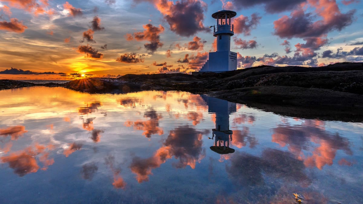 Faro al tramonto con il suo riflesso nell'acqua - la luce che torna dopo il buio